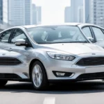 Srebrny Ford Focus MK4 w nowoczesnym miejskim otoczeniu, widok z przodu pod kątem.