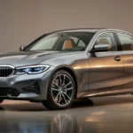 Szary sedan BMW serii 3 G20 w studiu, widok z przodu pod kątem, podkreślający dynamiczną linię nadwozia i reflektory.