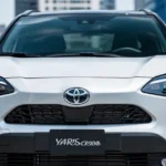 Nowoczesna biała Toyota Yaris Cross zaparkowana w miejskiej scenerii w świetle dziennym.