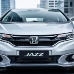 Srebrna Honda Jazz IV zaparkowana na tle nowoczesnego miasta, widok z przodu na reflektory i grill.