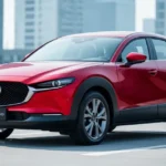 Metalicznie czerwona Mazda CX-30 zaparkowana na tle miejskiej architektury w świetle dziennym.