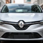 Srebrne Renault Clio V zaparkowane na nowoczesnej ulicy, widok na przednią część nadwozia z widocznymi detalami reflektorów.