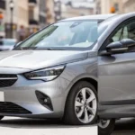 Srebrzystoszary Opel Corsa F zaparkowany na miejskiej ulicy w słoneczny dzień.