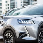 Srebrny SUV Peugeot 2008 II zaparkowany pod kątem, widoczny nowoczesny przód z charakterystycznymi światłami LED.
