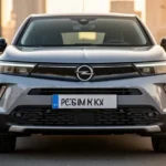 Srebrny Opel Mokka II z nowoczesnymi reflektorami LED, zaparkowany na asfalcie w świetle zachodzącego słońca.