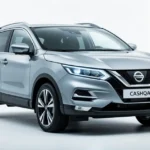 Srebrny Nissan Qashqai III widziany od przodu i z boku na czystym, białym tle w oświetleniu studyjnym.