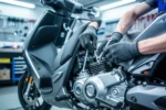 Mechanik w rękawicach naprawiający silnik nowoczesnego skutera w profesjonalnym warsztacie.