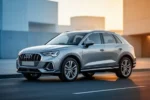 Srebrne Audi Q3 F3 zaparkowane na asfaltowej drodze w otoczeniu minimalistycznej architektury podczas złotej godziny.