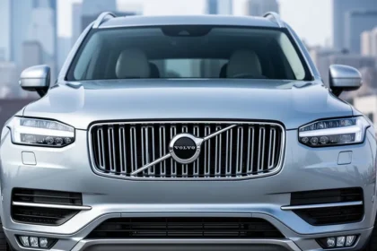 Przód srebrnego Volvo XC90 II z widocznym eleganckim grillem i światłami LED na tle miejskiego krajobrazu.