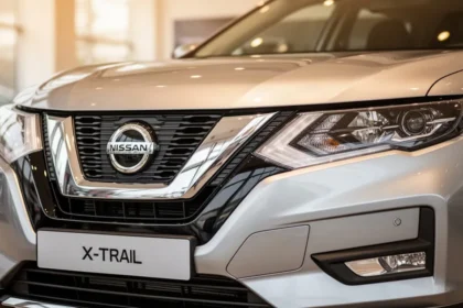 Zbliżenie na srebrny przód Nissana X-Trail IV z widocznymi reflektorami i wlotem powietrza w salonie samochodowym.