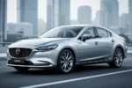 Srebrna Mazda 6 zaparkowana na nowoczesnej drodze asfaltowej na tle rozmytego krajobrazu miejskiego.